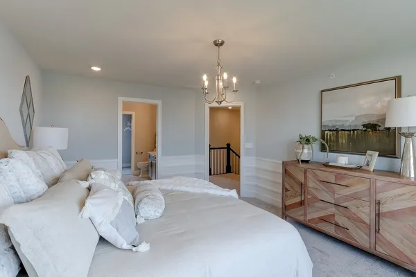 a spacious bedroom with a bed and a chandelier