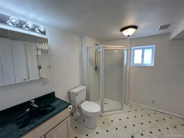 a bathroom with a granite countertop sink a toilet a mirror and shower