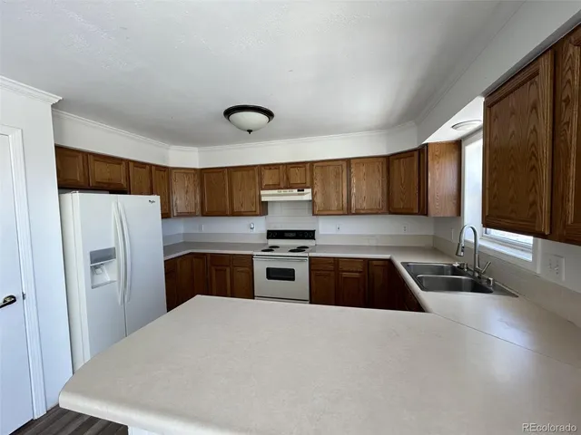 a kitchen with granite countertop a refrigerator and a stove top oven