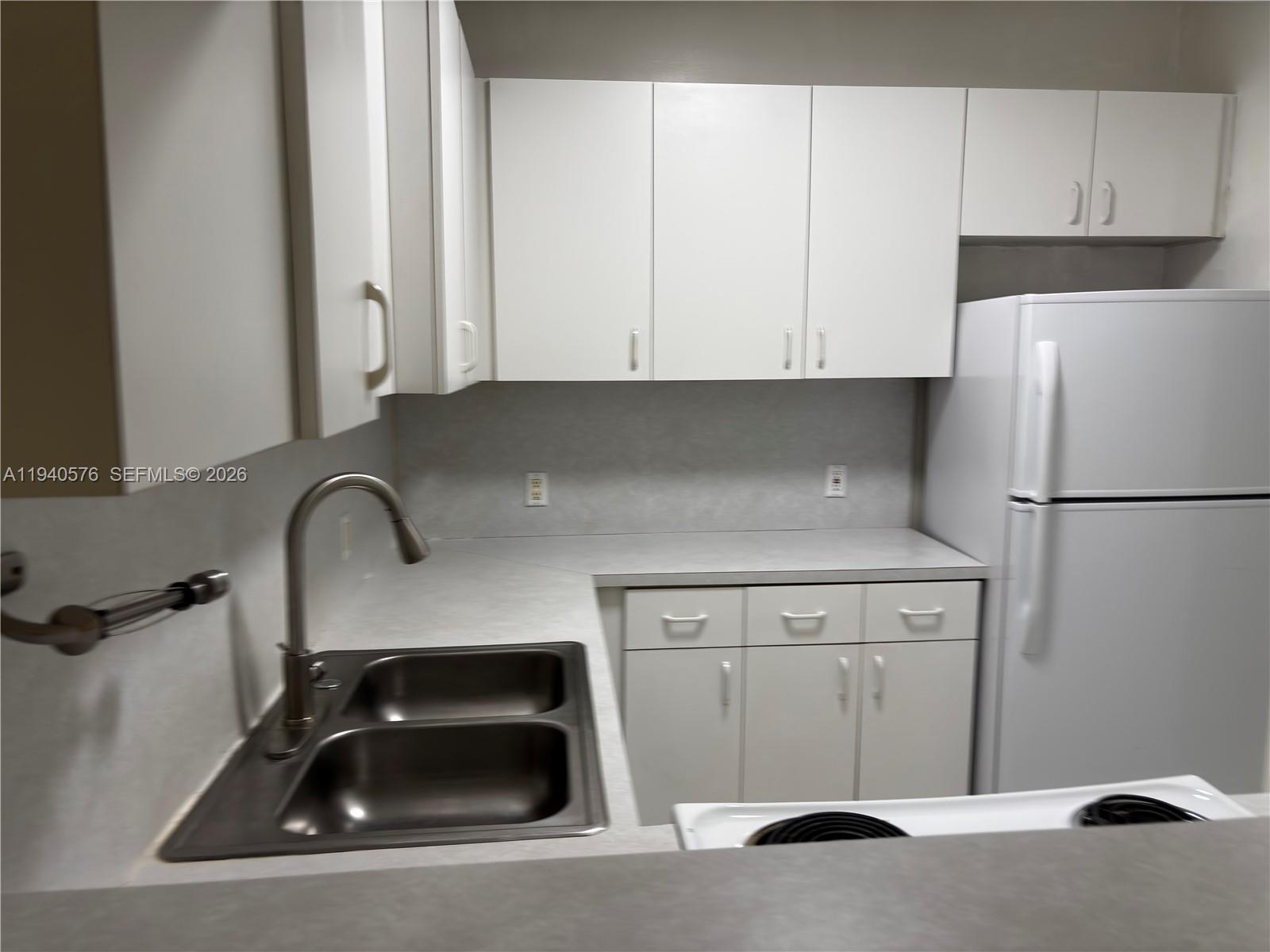 12645 Southwest 91st Street, Unit 2014 Miami, FL 33186 - Photo 6 of 15 a kitchen with a sink a refrigerator and cabinets