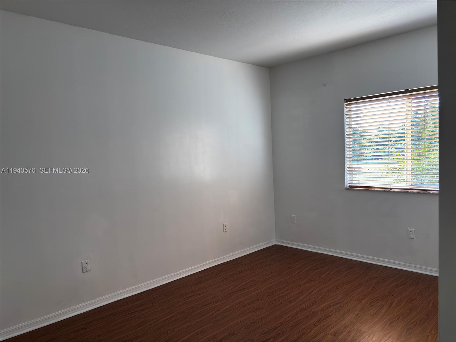 12645 Southwest 91st Street, Unit 2014 Miami, FL 33186 - Photo 7 of 15 a view of an empty room with wooden floor and a window
