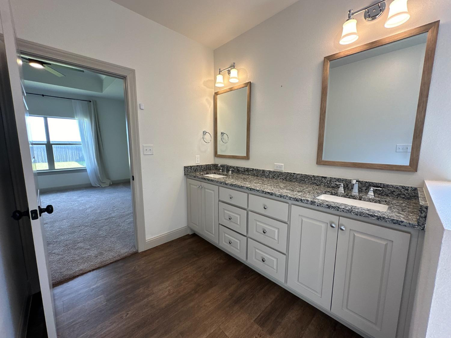 6959 103rd Street Lubbock, TX 79424 - Photo 19 of 49 a bathroom with a granite countertop sink and a mirror