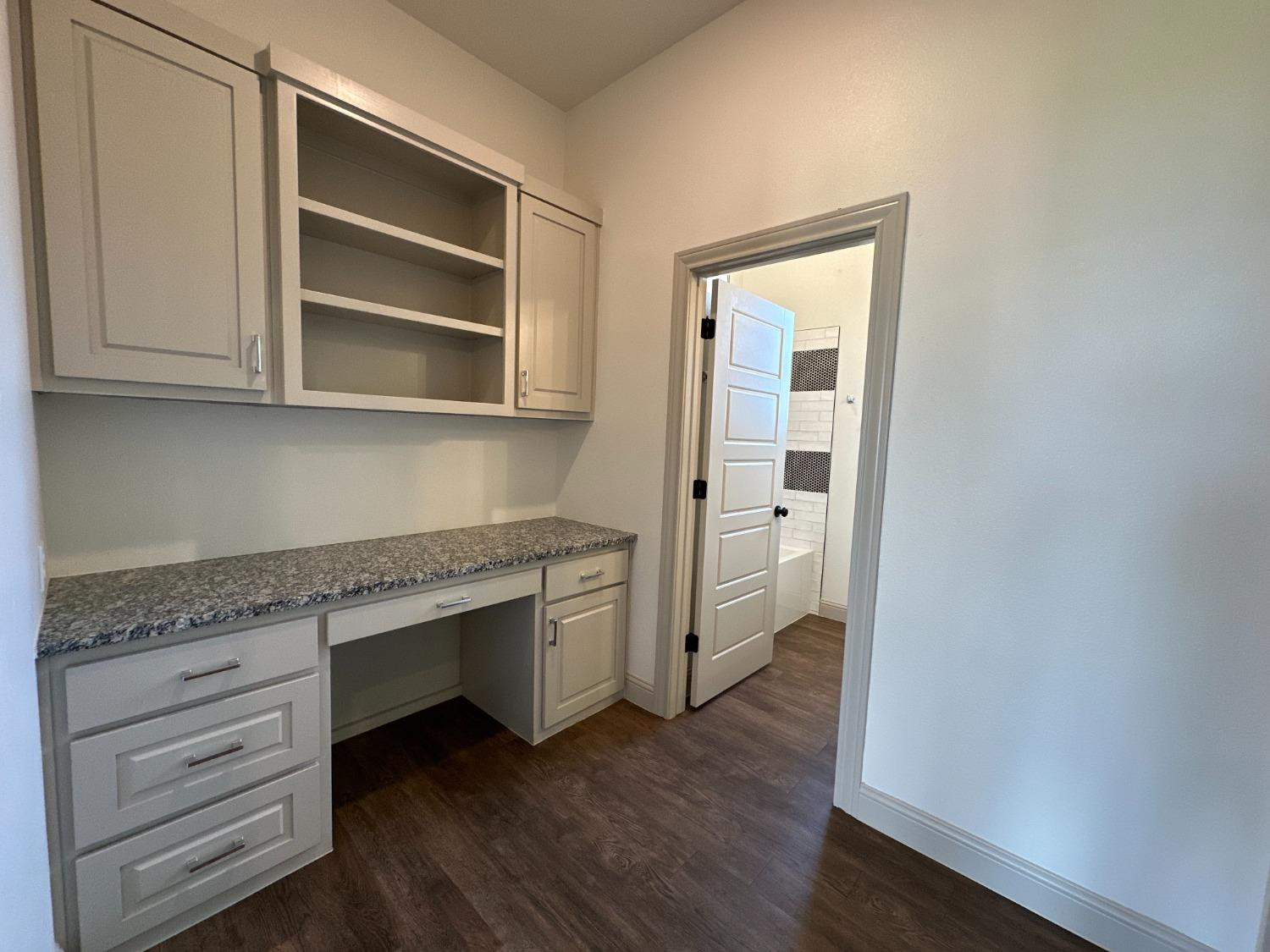 6959 103rd Street Lubbock, TX 79424 - Photo 20 of 49 a kitchen with granite countertop white cabinets and wooden floor