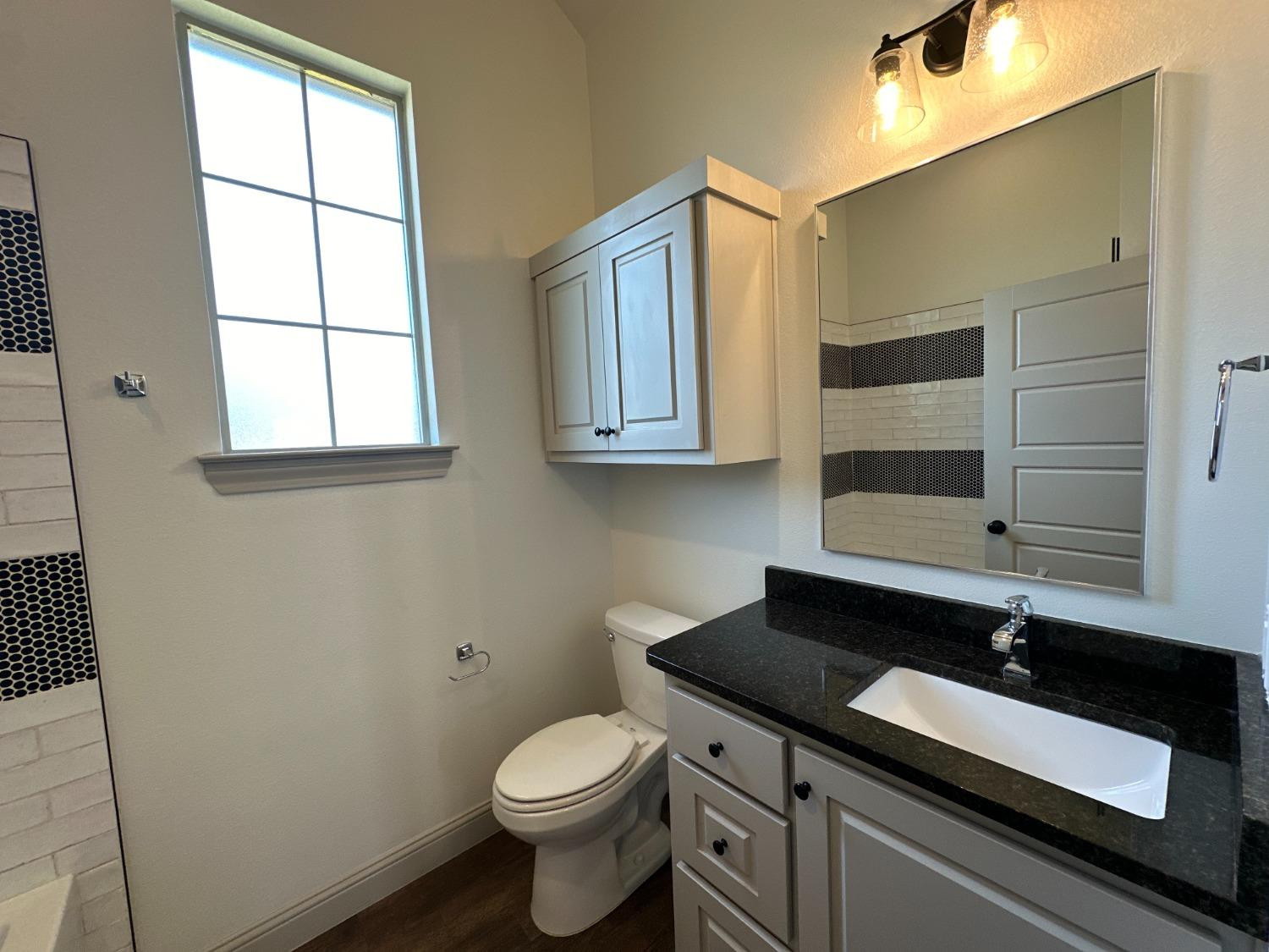 6959 103rd Street Lubbock, TX 79424 - Photo 21 of 49 a bathroom with a sink a toilet and mirror