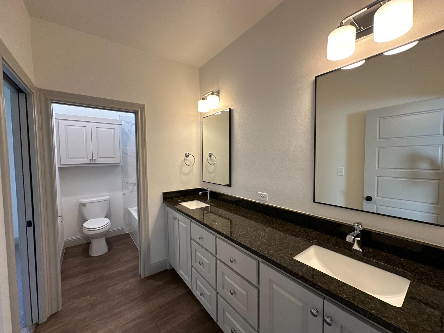6959 103rd Street Lubbock, TX 79424 - Photo 38 of 49 a bathroom with a granite countertop sink a toilet and a mirror