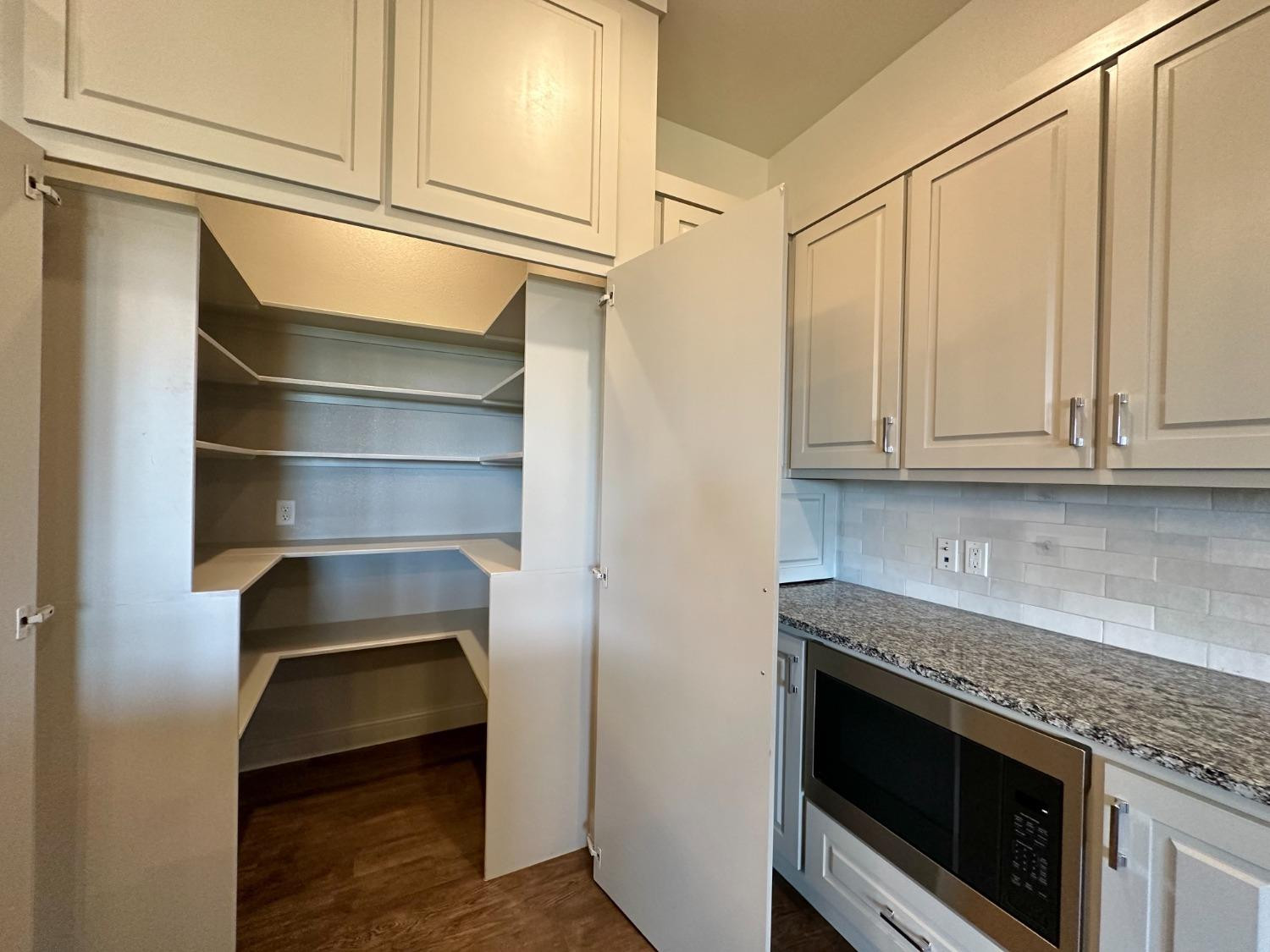 6959 103rd Street Lubbock, TX 79424 - Photo 7 of 49 a kitchen with granite countertop white cabinets and stainless steel appliances