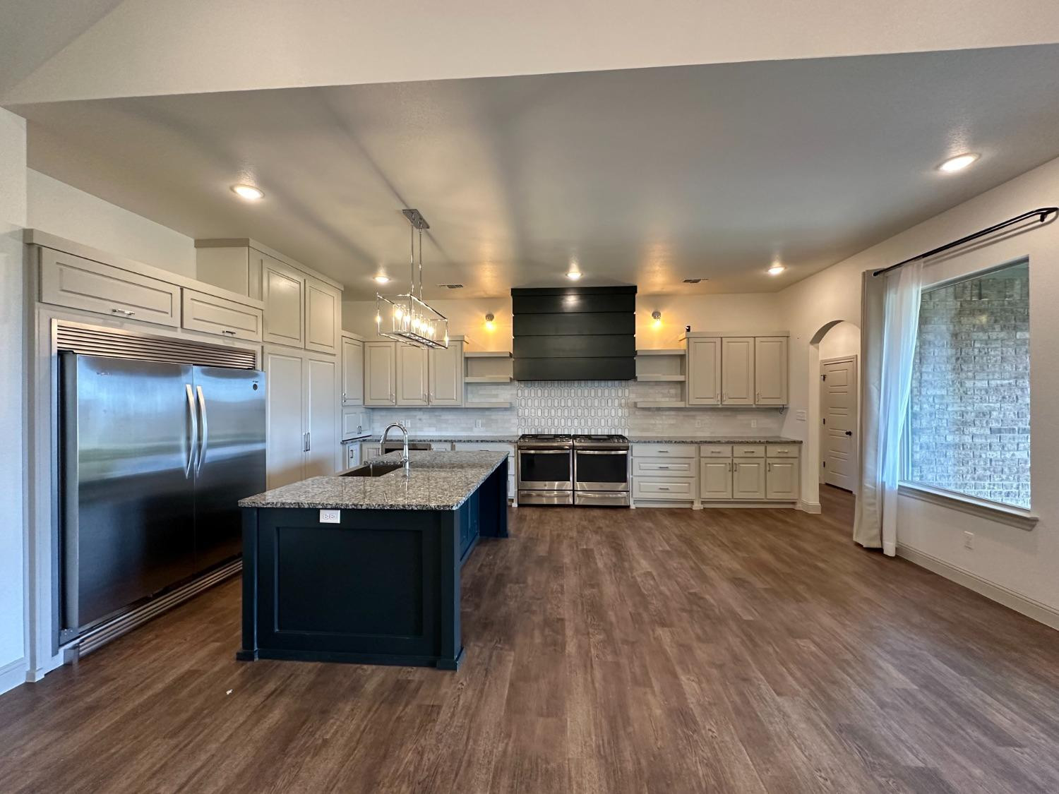 6959 103rd Street Lubbock, TX 79424 - Photo 9 of 49 a kitchen with stainless steel appliances kitchen island granite countertop a stove and a refrigerator