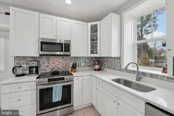 a large white kitchen with stainless steel appliances lots of counter space and wooden floor