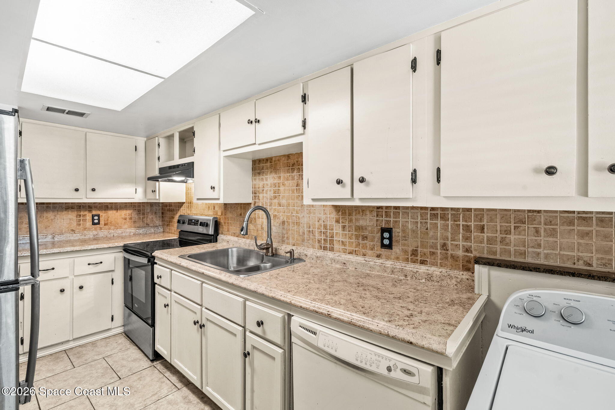 500 Catalina Road, Unit 402 Cocoa Beach, FL 32931 - Photo 9 of 34 a kitchen with white cabinets sink and white appliances