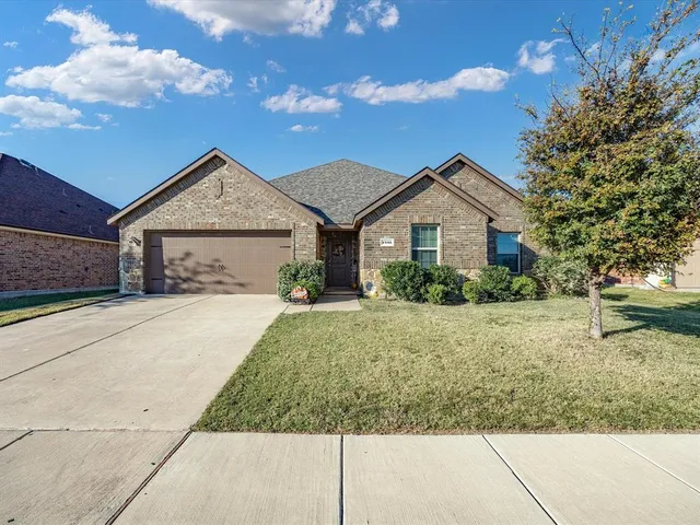 a view of a house with a yard and table and chairs under an umbrella