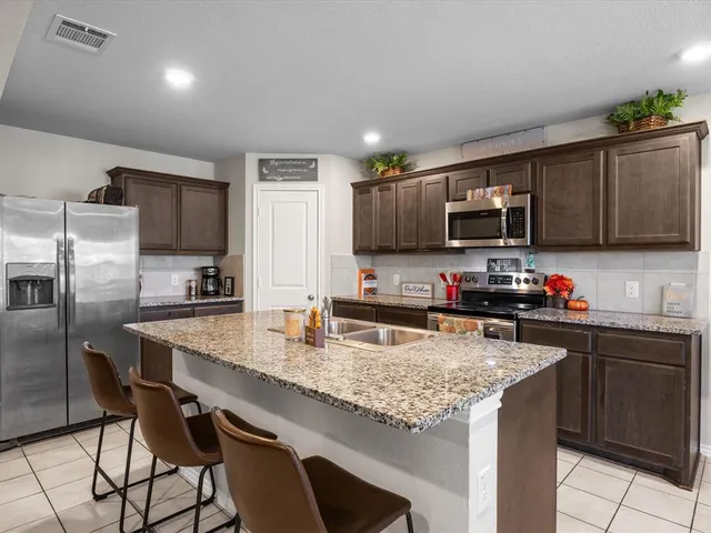a kitchen with granite countertop a stove a sink a dining table and chairs