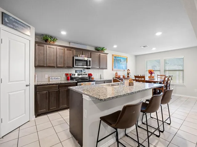 a kitchen with kitchen island granite countertop a sink counter top space appliances and cabinets