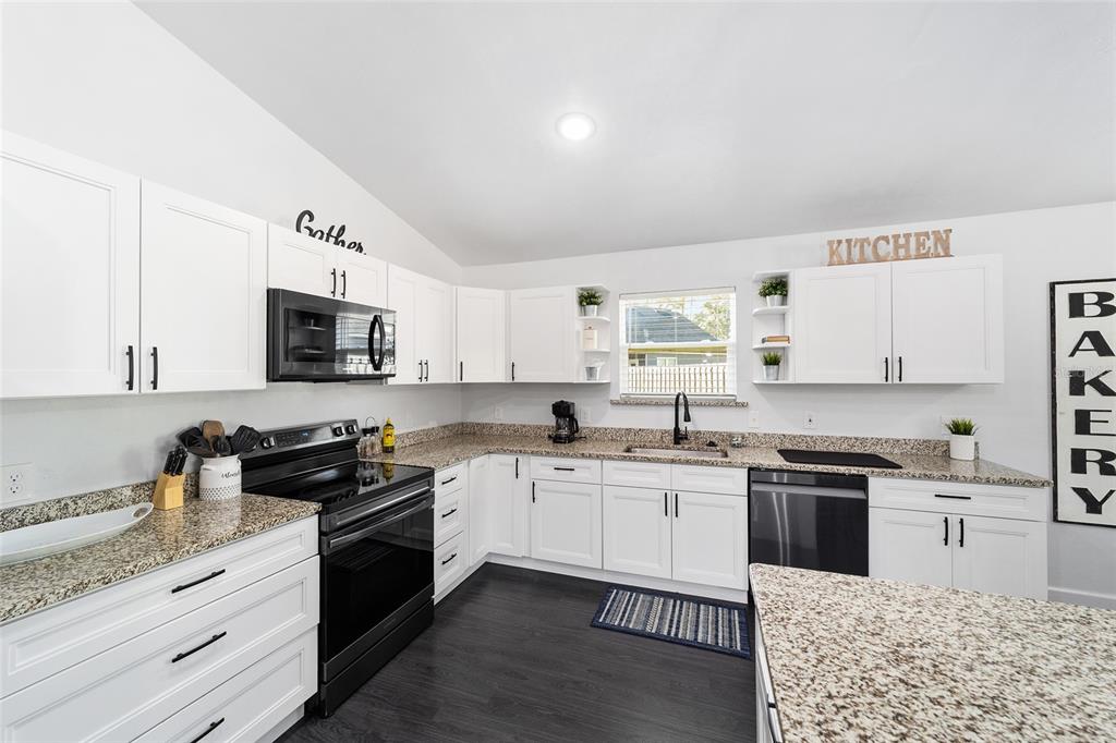 16668 Northwest 191st Way High Springs, FL 32643 - Photo 8 of 38 a kitchen with stainless steel appliances granite countertop a stove top oven a sink dishwasher and white cabinets with wooden floor