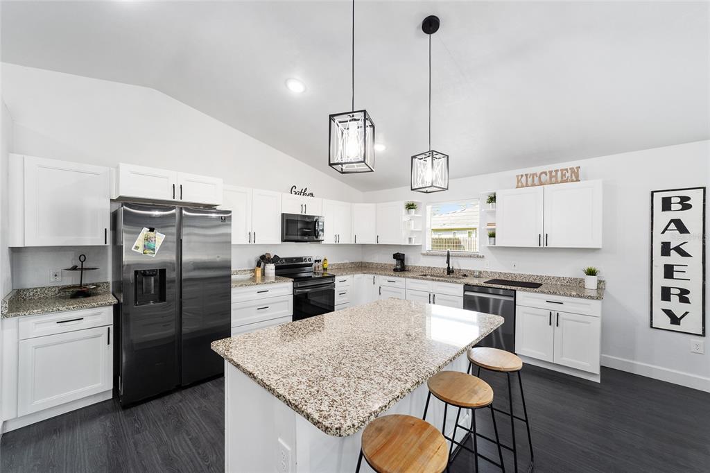 16668 Northwest 191st Way High Springs, FL 32643 - Photo 9 of 38 a kitchen with stainless steel appliances granite countertop a sink a stove a refrigerator cabinets a dining table and chairs
