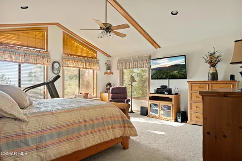 a bedroom with a bed flat screen tv and a large window