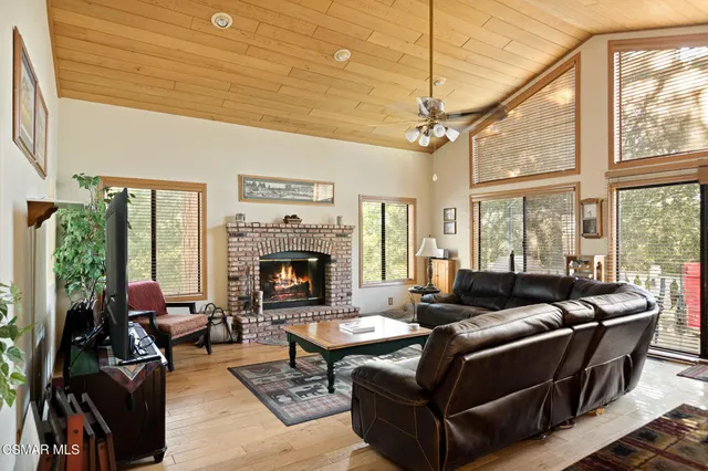 a living room with furniture a fireplace and floor to ceiling windows
