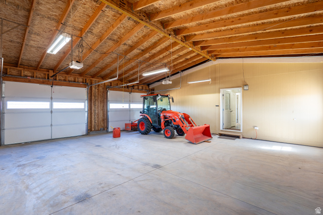 700 East Peter Springs Road Monticello, UT 84535 - Photo 32 of 57 Spacious garage featuring two overhead doors with window panels, exposed wood ceiling beams, concrete flooring, and a side entrance door