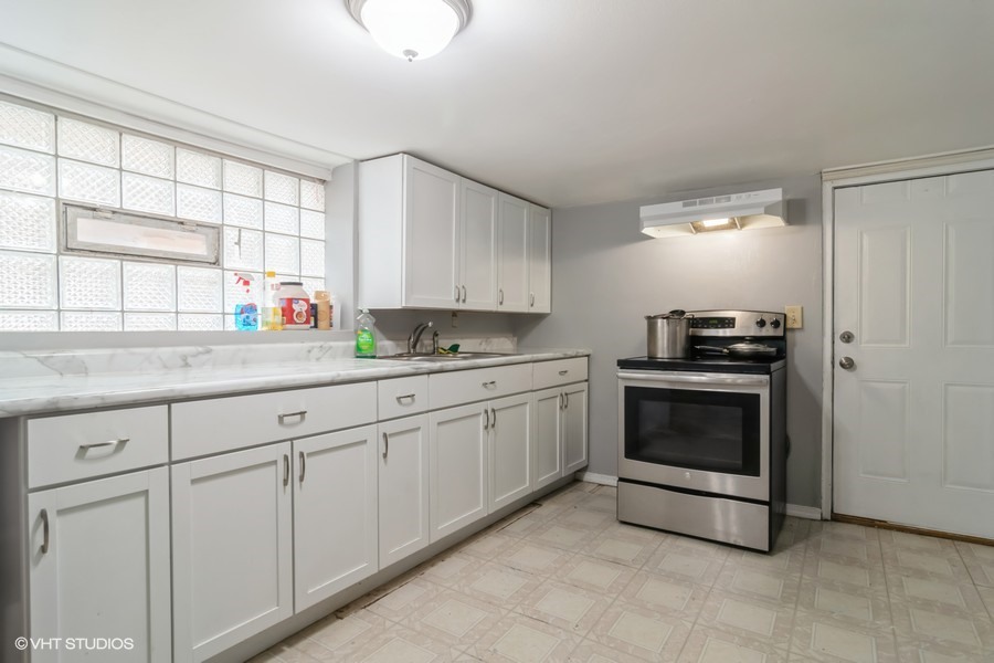 2180 North Mango Avenue Chicago, IL 60639 - Photo 11 of 18 a kitchen with granite countertop white cabinets and white appliances