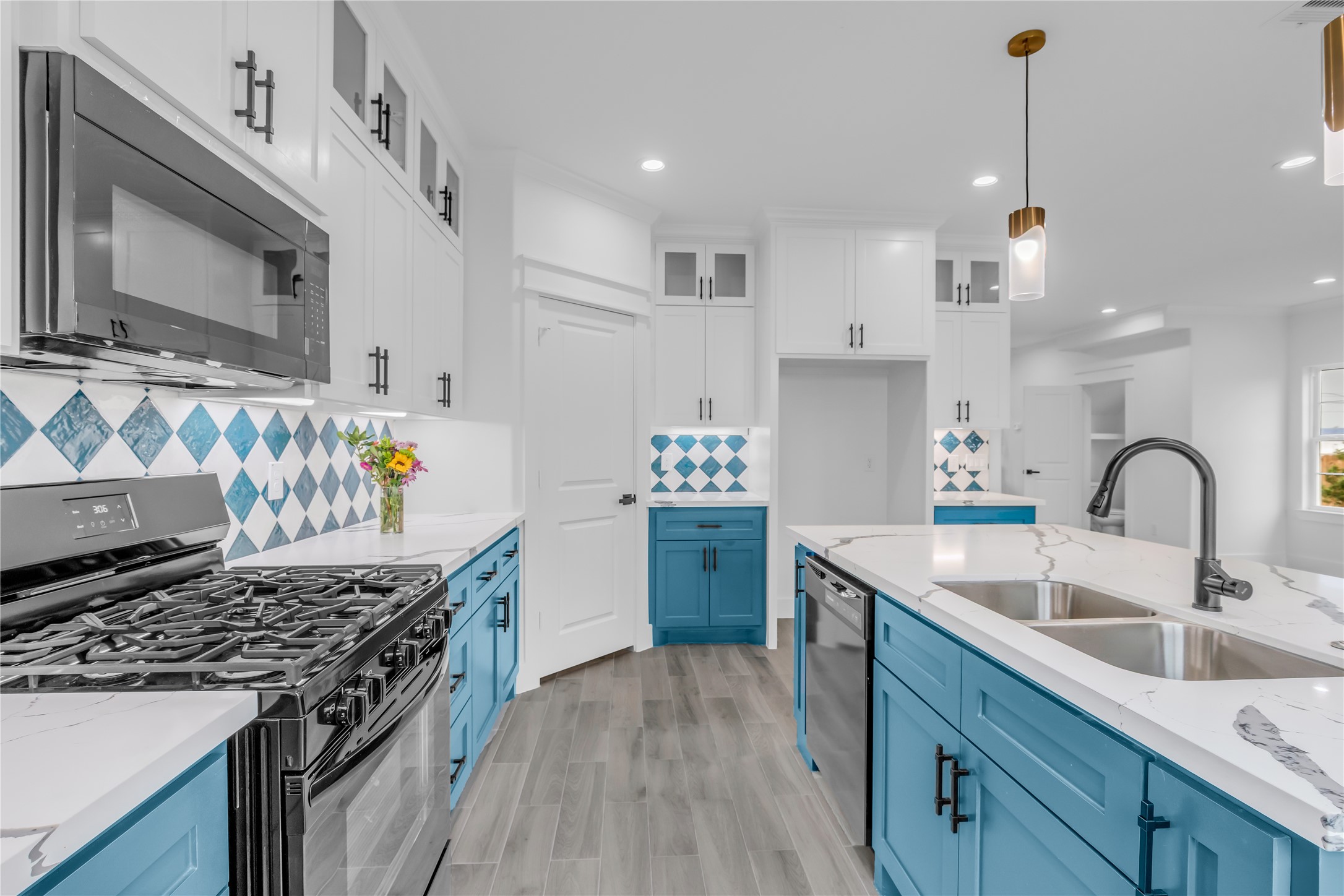 3168 Golfcrest Houston, TX 77087 - Photo 10 of 30 Discover the heart of your home in this stunning kitchen, featuring vibrant blue cabinetry, sleek stainless steel appliances, and elegant marble countertops, all accented by stylish geometric backsplash tiles for a perfect blend of modern flair and functionality.