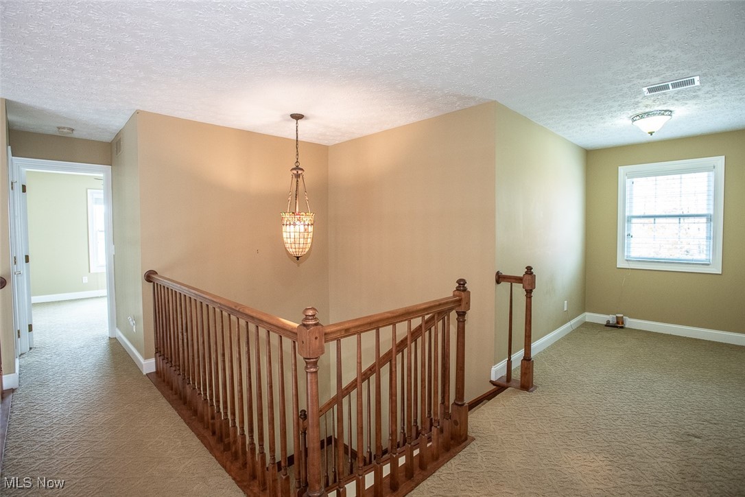 630 Rundle Street Lagrange, OH 44050 - Photo 40 of 49 Hallway with an upstairs landing, carpet flooring, and a textured ceiling