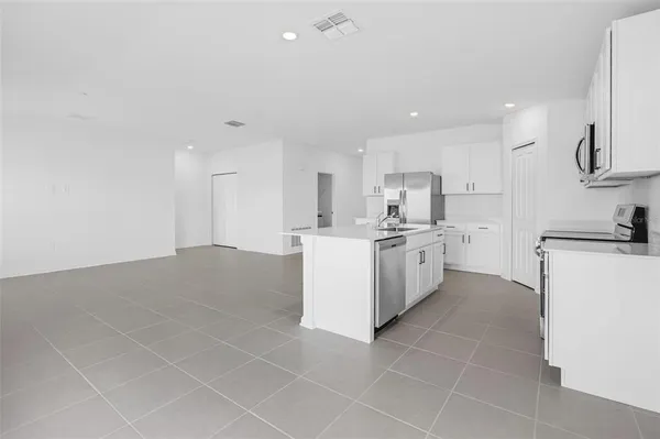 a kitchen with a sink a stove top oven and white cabinets