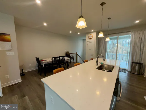 a large white dining hall with stainless steel appliances a dining table and chairs with wooden floor