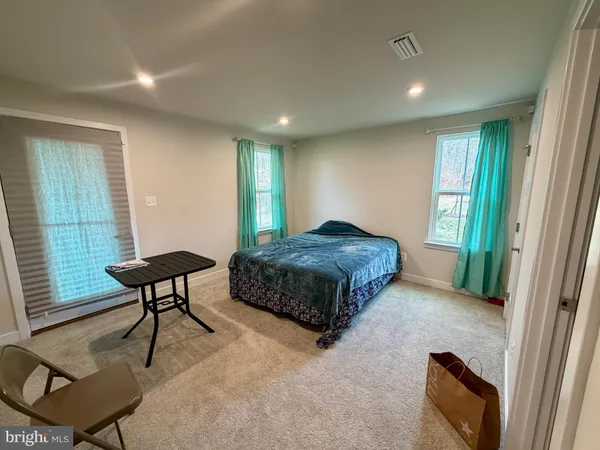 a bedroom with a bed a chair and a large window