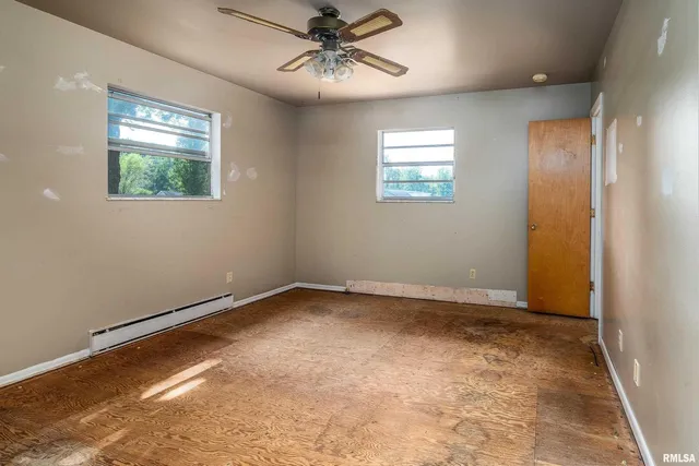 an empty room with windows and fan