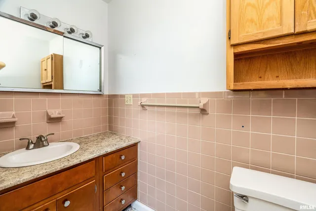 a bathroom with a granite countertop sink a mirror and a toilet
