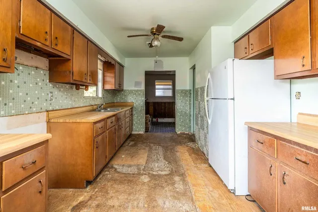 a kitchen with stainless steel appliances granite countertop a refrigerator a sink dishwasher and white cabinets with wooden floor