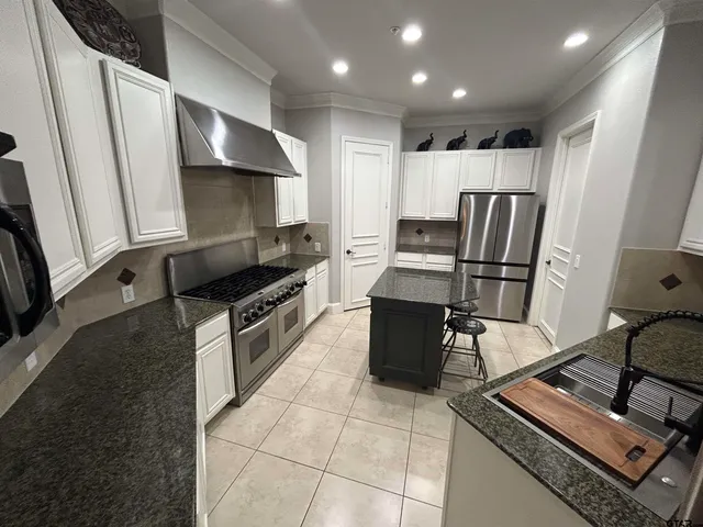 a kitchen with granite countertop a refrigerator and a stove top oven