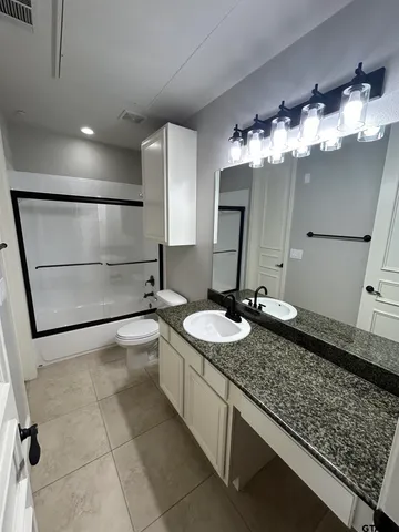 a bathroom with a granite countertop sink a toilet and mirror