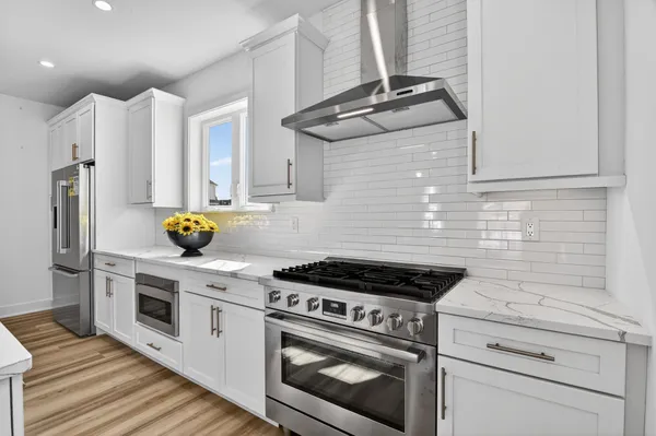 a kitchen with stainless steel appliances granite countertop white cabinets a stove a sink and dishwasher