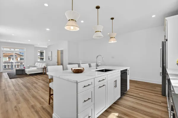 a kitchen with a sink dishwasher a dining table and chairs with wooden floor