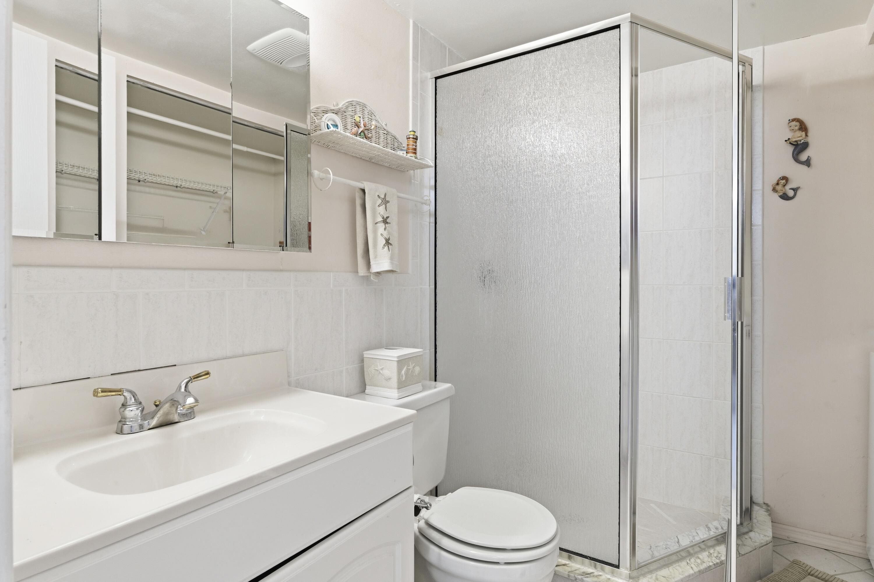 717 Highway 1, Unit 707 Jupiter, FL 33477 - Photo 15 of 33 a bathroom with a sink a mirror a toilet and shower