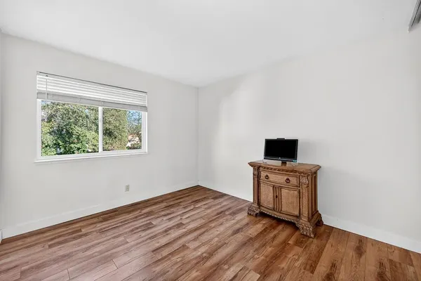 a view of empty room with wooden floor and fan