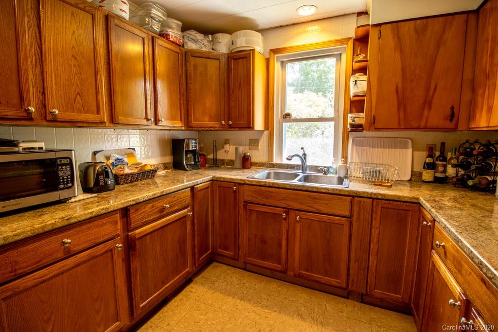 1271 Upper Brush Creek Road Fairview, NC 28730 - Photo 6 of 19 a kitchen with stainless steel appliances granite countertop wooden cabinets a sink and a window