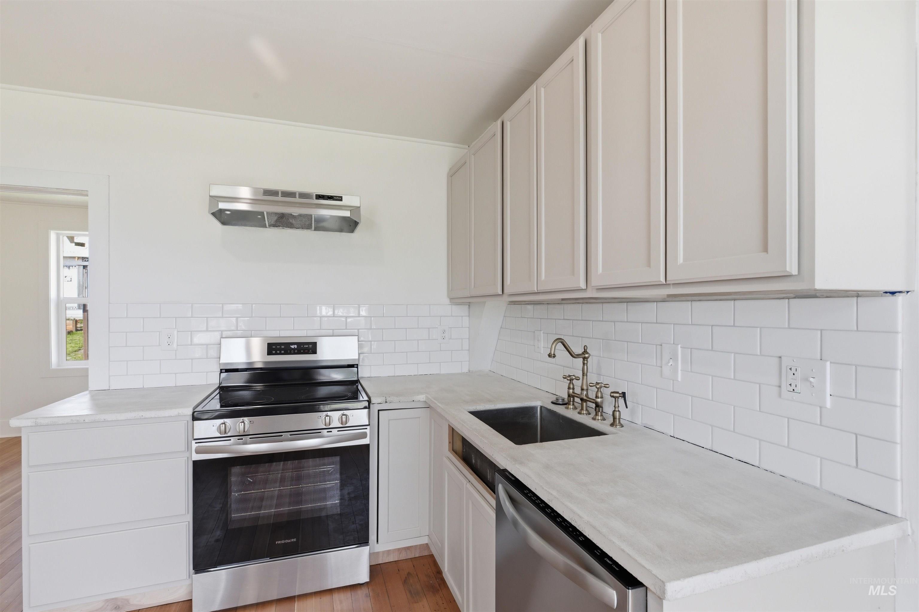 810 Pine Street Potlatch, ID 83855 - Photo 12 of 33 Kitchen featuring light-toned cabinetry, stainless steel appliances, a subway tile backsplash, and a double basin sink with a traditional-style faucet