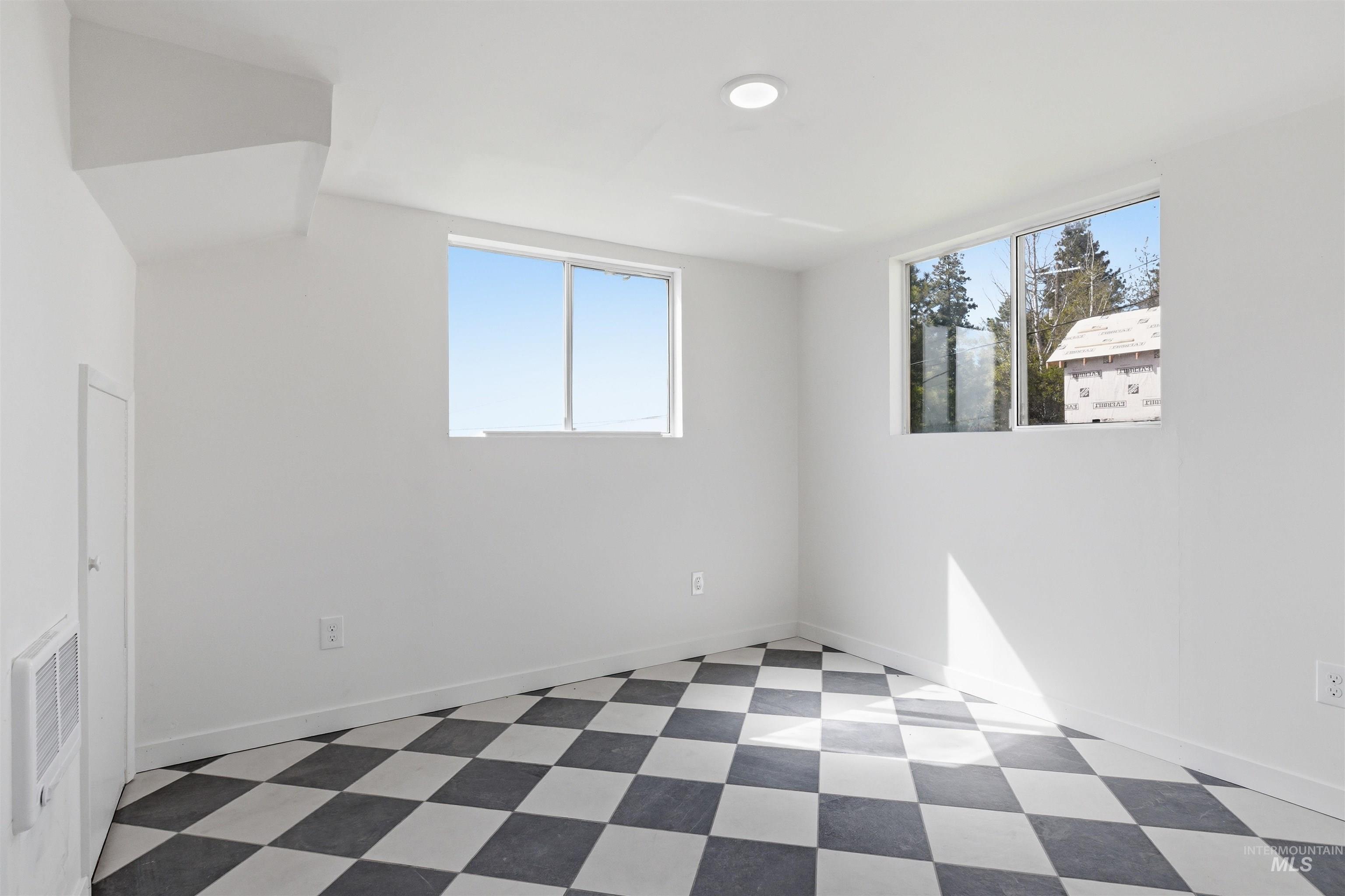 810 Pine Street Potlatch, ID 83855 - Photo 17 of 33 Bright room featuring two windows, checkered flooring, white walls, and a ceiling-mounted light fixture