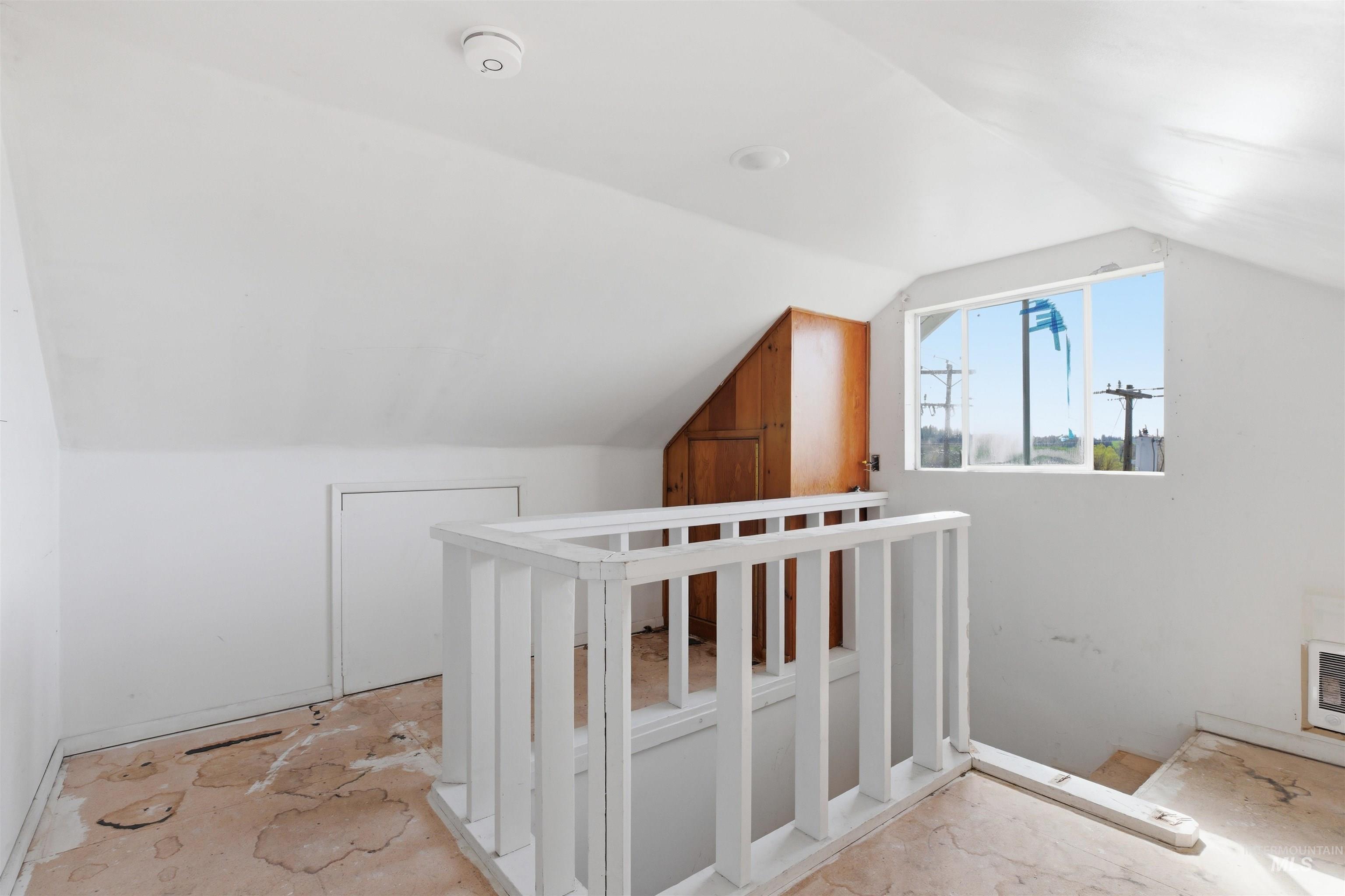 810 Pine Street Potlatch, ID 83855 - Photo 19 of 33 Attic space featuring sloped ceilings, a window, built-in wooden cabinetry, and a white painted balustrade