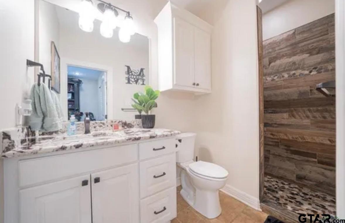 225 Clements Circle Tatum, TX 75691 - Photo 19 of 26 a bathroom with a granite countertop sink a toilet and a mirror