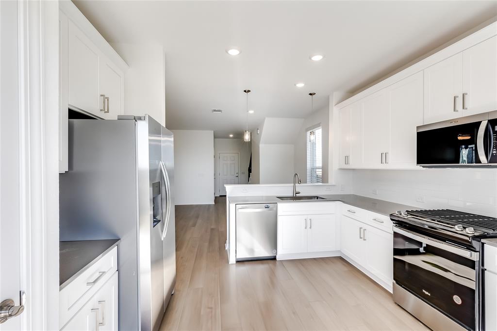 109 Bridge Deck Loop Kyle, TX 78640 - Photo 13 of 40 Kitchen featuring stainless steel appliances, decorative light fixtures, recessed lighting, white cabinets, and light wood-style flooring