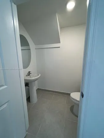 a white toilet sitting next to a white sink and vanity