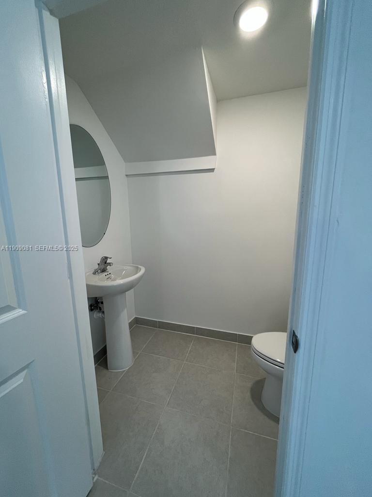28660 Southwest 134th Court, Unit 28660 Homestead, FL 33033 - Photo 3 of 12 a white toilet sitting next to a white sink and vanity