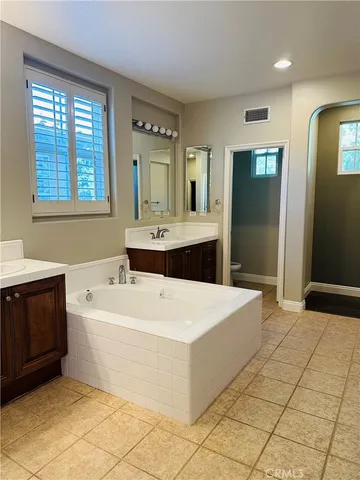 a spacious bathroom with a bathtub sink and mirror