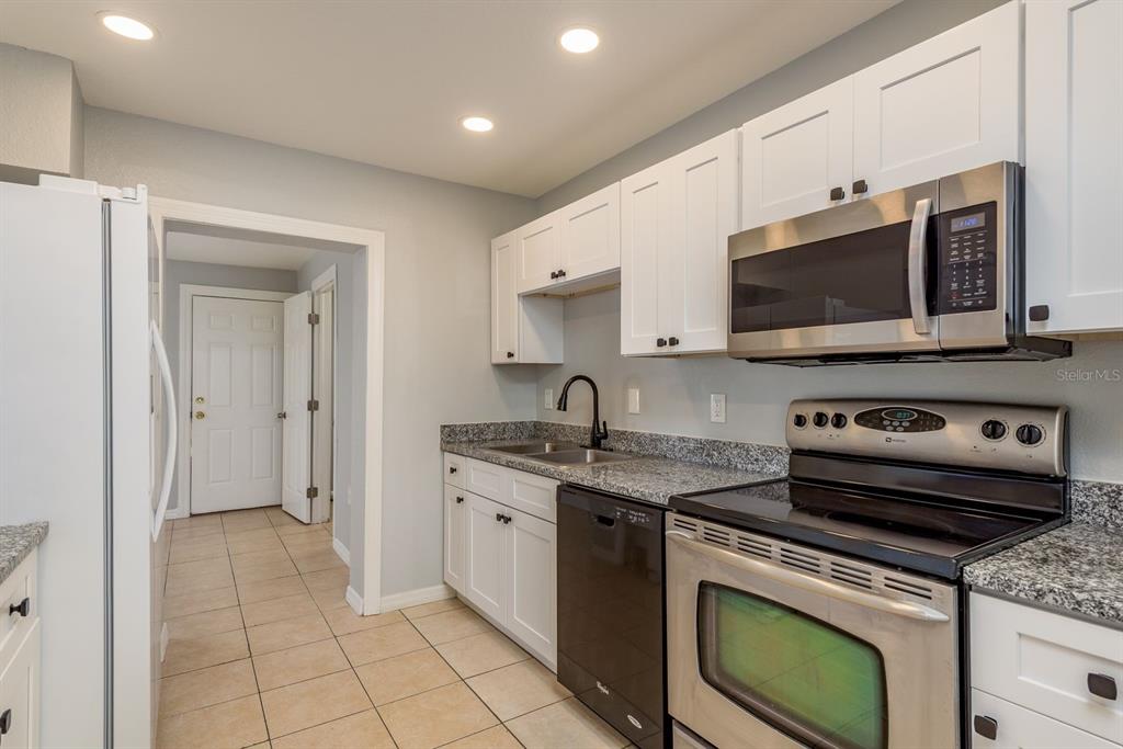13698 120th Street North Largo, FL 33778 - Photo 13 of 30 a kitchen with stainless steel appliances granite countertop a stove a microwave and a refrigerator