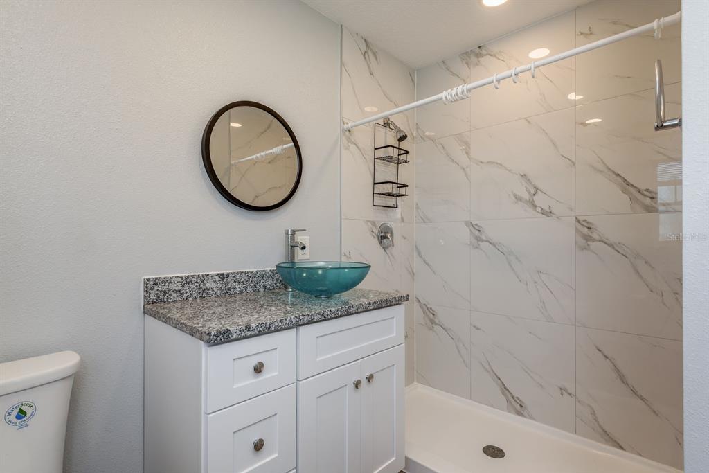 13698 120th Street North Largo, FL 33778 - Photo 18 of 30 a bathroom with a granite countertop sink a toilet and shower