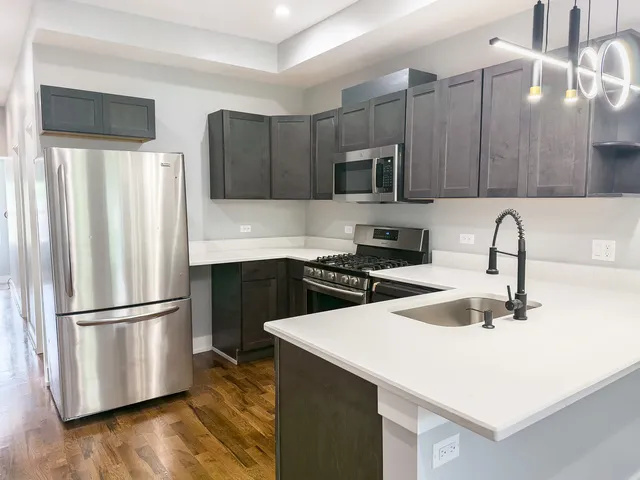 a kitchen with a sink a microwave a refrigerator and cabinets
