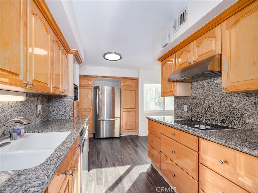 5411 Tyrone Avenue Sherman Oaks, CA 91401 - Photo 11 of 28 a kitchen with stainless steel appliances granite countertop a sink a stove and a wooden cabinets