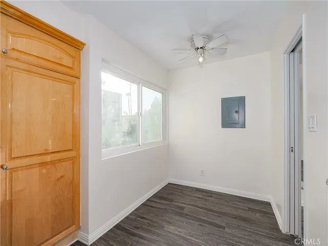 an empty room with wooden floor cabinet and windows
